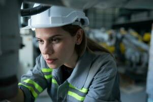 hembra técnico inspeccionando y reparando robótica brazo en robots hangar y prueba el operación de el máquina después siendo usado para un mientras, como bien como actualización el software y calibración foto