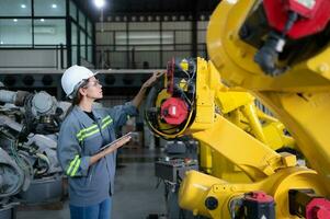 A female engineer installs a program on a robotics arm in a robot warehouse. And test the operation before sending the machine to the customer. photo