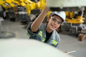 A female engineer installs a program on a robotics arm in a robot warehouse. And test the operation before sending the machine to the customer. photo