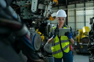 A female engineer installs a program on a robotics arm in a robot warehouse. And test the operation before sending the machine to the customer. photo