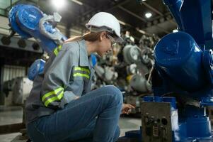 A female engineer installs a program on a robotics arm in a robot warehouse. And test the operation before sending the machine to the customer. photo