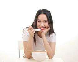 Beautiful young south east Asian woman holding chinese empty chopstick soup spoon bowl utensil pretend acting posing see eat taste feed offer satisfaction yummy white background happy photo