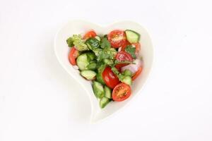 indio subcontinente estilo tomate Pepino cebolla chile cilantro ensalada en ciervo forma blanco plato en blanco antecedentes foto