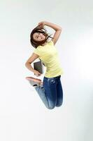 Yong Asian youth girl in casual dress holding book notebook look at camera jump high happy on white background photo