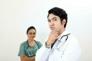 young asian malay chinese male female doctor on white background hand on chin thinking funny witty at camera photo