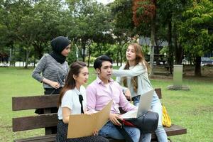 joven asiático malayo chino hombre mujer al aire libre parque libro archivo carpeta ordenador portátil computadora teléfono sentar estar estudiar mezclarse foto