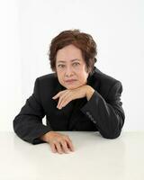 Elderly asian Chinese female on white background wearing black suit thinking chin rest on back of hand photo