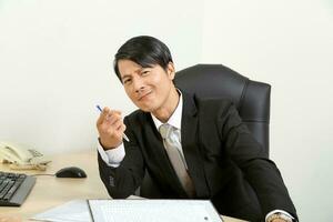 asian man point think sitting at office desk photo