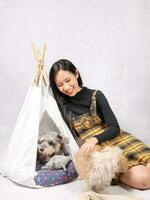Young attractive Asian woman playing caring tricks cute little furry dog in tent photo