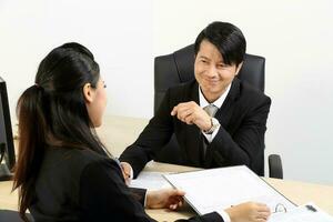 Young Asian male female wearing suit sitting at office desk thinking meeting disucsing sign document agreement photo