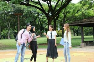 joven asiático malayo chino hombre mujer al aire libre parque libro archivo carpeta ordenador portátil computadora teléfono sentar estar estudiar mezclarse foto