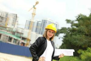 mujer malayo chino trabajador ingeniero administración difícil la seguridad sombrero casco a construcción sitio participación plan Mira a cámara foto