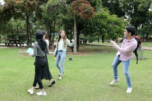 joven asiático malayo chino hombre mujer al aire libre parque libro archivo carpeta ordenador portátil computadora teléfono sentar estar estudiar mezclarse foto