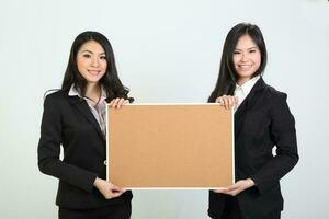 Two young asian malaysian business office woman holding blank copy text space sign board on white background photo