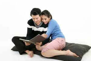 South East Asian Chinese couple husband wife sit on floor read see book album white background photo