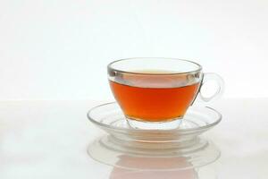 Clear licker tea in a transparent glass cup saucer spoon on white background photo