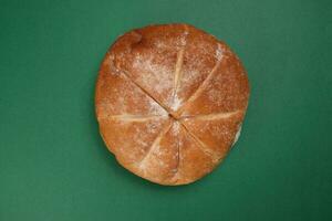 Freshly baked bread loaf round on green background photo