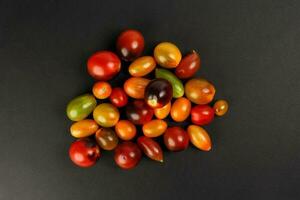 Fresh ripe mixed tomato verity assorted color on black background photo