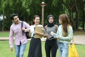 joven asiático malayo chino hombre mujer al aire libre parque libro archivo carpeta ordenador portátil computadora teléfono sentar estar estudiar mezclarse foto