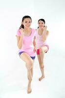 Two beautiful young south east Asian Chinese woman exercise workout yoga one leg folded up stretch on white background photo