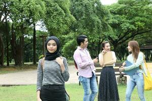 joven asiático malayo chino hombre mujer al aire libre parque libro archivo carpeta ordenador portátil computadora teléfono sentar estar estudiar mezclarse foto