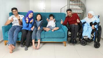 Group portrait of southeast Asian adult child girl male female look happy smile emotion expression wave thumbs up point sit on blue sofa. They are autistic down syndrome adhd paralyzed wheelchair photo