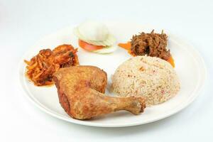 Indonesian royal dish nasi bojari with deep spiced deep fried chicken leg sambal prawn curry beef rendang boild egg cucumber and tomato slice photo
