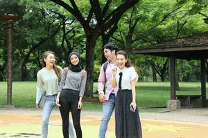 joven asiático malayo chino hombre mujer al aire libre parque libro archivo carpeta ordenador portátil computadora teléfono sentar estar estudiar mezclarse foto