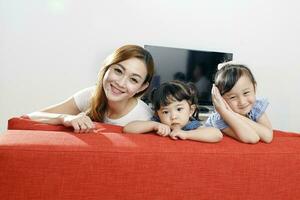 Parent mother father little child boy girl brother sister happy smile looking over the sofa photo