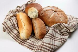 Freshly baked bread loaf bun roll round long mix verity wrapped in checkered kitchen fabric napkin towel over white background photo