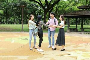 joven asiático malayo chino hombre mujer al aire libre parque caminar estar estudiar hablar discutir punto ordenador portátil archivo libro mochila mezclarse divertido reunirse saludar foto