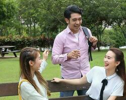 Young asian malay chinese man woman outdoor on park bench mingle talk discuss happy point photo