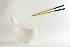 Empty oriental Japanese Chinese soup bowl spoon chopstick elevated flying in air off white photo