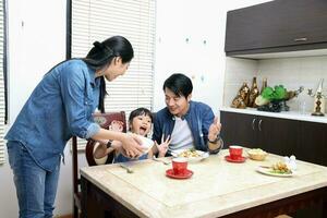 South east asian yong family daughter child parent father mother at dining table eating food lunch photo