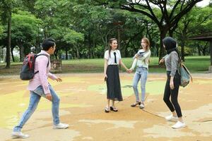 joven asiático malayo chino hombre mujer al aire libre parque caminar estar estudiar hablar discutir punto ordenador portátil archivo libro mochila foto