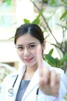 South East Asian young Malay Chinese woman medical doctor stethoscope stand one finger photo