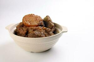 Asian style Beef bhuna dry curry with potato in ceramic bowl over white background photo