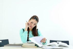 Yong Asian youth girl in casual dress sit at table book notebook pen study read on white background photo