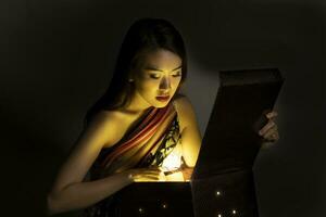 Asian woman opening mystic book box magical light dark background photo