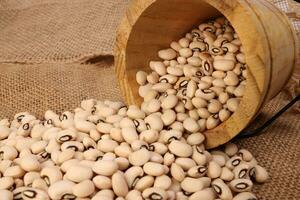 Blackeye beans in wooden small bucket on jute yarn fabric background photo