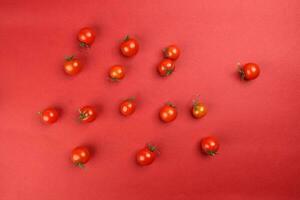 Red ripe cherry tomato with stem on red paper background copy text space photo