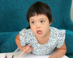 Sureste asiático pequeño pequeño niña niño jugando dibujo garabatear bolígrafo papel ella tener dwon síndrome foto