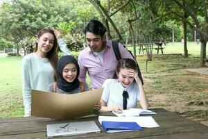 joven asiático malayo chino hombre mujer al aire libre parque libro archivo carpeta ordenador portátil computadora teléfono sentar estar estudiar mezclarse foto