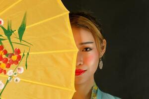 Asian woman in tractional kebaya carrying umbrella on black background photo