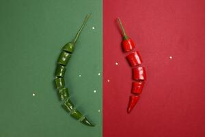 green red chilli pepper on green red paper background cut pieces seeds photo