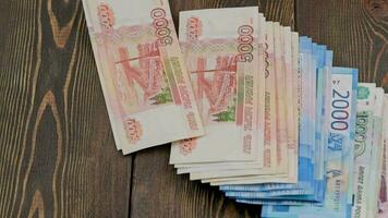 stack of russian rubles banknotes dropping on wooden surface and sliding video