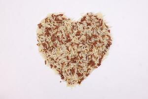 Mixed low glycaemic index healthy rice grain basmati millet buckwheat red rice hart shape on white background photo