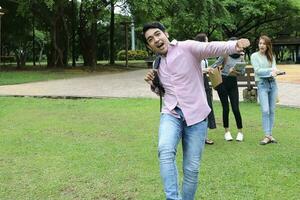 joven asiático malayo chino hombre mujer al aire libre parque caminar estar estudiar hablar discutir punto ordenador portátil archivo libro mochila contento adelante foto