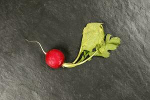 Small red radish on black slate background photo