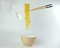 Yellow noodle soup elevated flying suspended in air bowl spoon and chopstick on white background photo